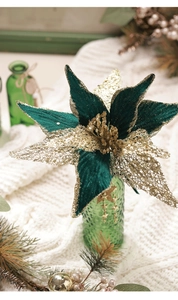 Close-up of artificial green velvet Christmas flower with gold sequins and pine decor