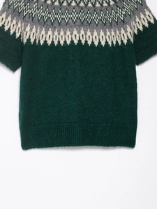 Macro detail of dark green knitwear with Fair Isle geometric patterns and ribbed textures