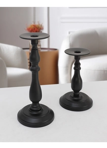 Close-up of matte black iron candlesticks in two sizes on a white marble tabletop
