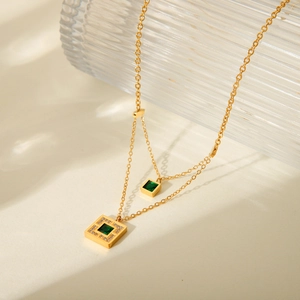 Detailed close-up of double-layered gold necklace with green emerald-cut zircon pendants