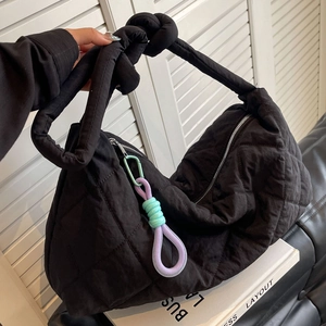 Large black quilted tote bag with colorful braided charms and a soft crossbody strap