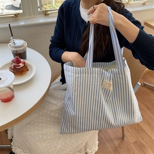 Close-up of blue and white striped canvas tote bag in a cozy cafe setting