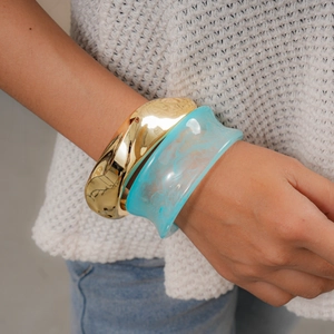 Detailansicht eines polierten Goldarmreifens und eines blauen Marmorharz-Armbands