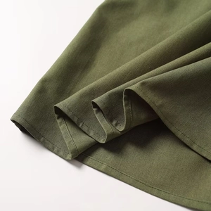 Detailed close-up of olive green linen fabric texture and precise stitching on the hemline