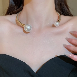 Close-up of a gold metal choker necklace featuring two large white pearls on a model