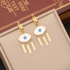 Golden evil eye earrings with white enamel and blue center on a jewelry box