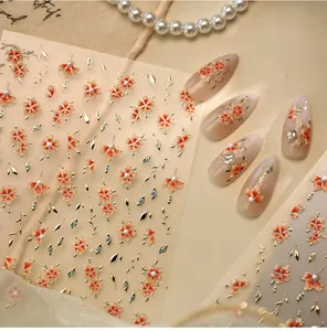 Macro view of floral nail stickers with red petals, gold leaves and pearl accents