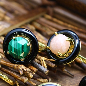 Macro shot of malachite and moonstone rings with gold settings on a wooden branch