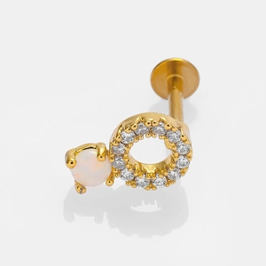 Détail du piercing labret doré avec anneau pavé de cristaux et opale blanche sur fond blanc