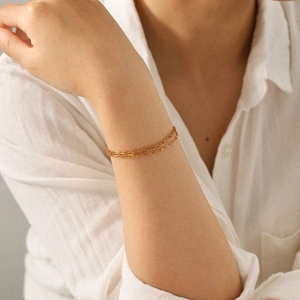 Detailed view of layered 18K gold triple-strand bracelets on a model's wrist