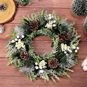 Couronne de Noël givrée avec pommes de pin et baies blanches sur un fond en bois rustique