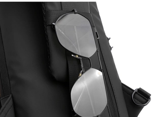 Detail of pilot sunglasses hooked on a black waterproof chest bag with a USB port