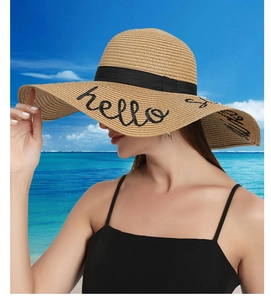 Close-up of wide brim straw hat with Hello Sunshine embroidery and black ribbon