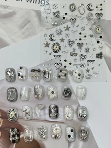 Macro shot of silver metallic nail stickers with heart, moon and star gothic patterns