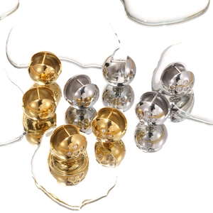 Spherical gold and silver hoop earrings with diamond heart accents on reflective surface