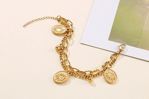 Detail of gold double-layer chain bracelet featuring sun medallions and metallic beads