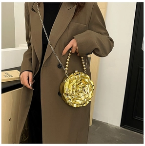 Close-up of golden rose-shaped fashion bag with metallic finish and bead handle