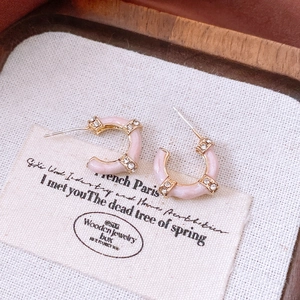 Detailed close-up of pink enamel bamboo-style C-shape earrings with gold finish and rhinestones