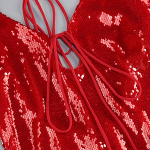 Close-up of red sequined dress featuring detailed lace-up chest ties and fabric texture