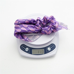 Detailed view of periwinkle floral hair ribbon on a scale showing 11.3g weight