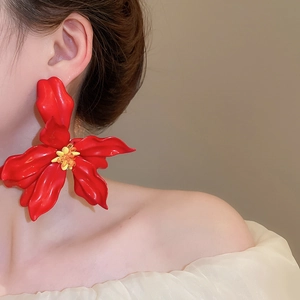 Close-up of a large red acrylic flower earring with yellow beads worn by a fashion model