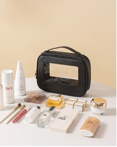 Dettaglio del beauty case in pelle nera con finestra trasparente e manico superiore