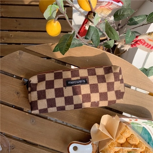 Close-up of a brown checkered corduroy pencil case on a wooden bench with lemon decor