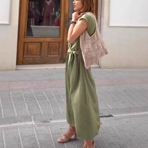 Detail of waist tie on sage green maxi dress paired with a woven summer tote bag