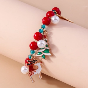 Close-up of Christmas beaded bracelet with reindeer and tree charms on pink stand