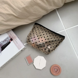 Translucent black mesh heart makeup bag stored with cosmetics in a lifestyle setting