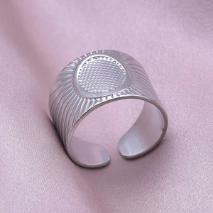 Macro detail of silver adjustable stainless steel ring with oval mesh texture on pink silk
