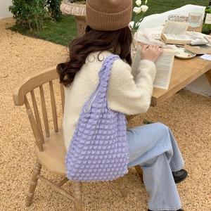 Detailed close-up of a purple textured bubble cloud tote bag worn in a casual outdoor setting