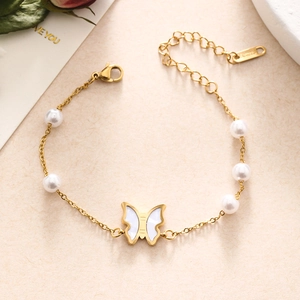 Close-up of gold stainless steel butterfly and pearl bracelet on aesthetic background