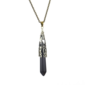 Detail of hexagonal black crystal pendant with vintage bronze hollow metal cap and chain