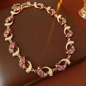 Macro shot of vintage necklace featuring red enamel floral patterns and sparkling crystals