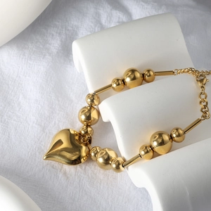 Detailed view of polished 18k gold heart pendant with layered beads and adjustable chain