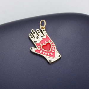 Detailed macro view of a gold-plated palm pendant with a red heart and colorful enamel