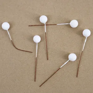 Macro view of six white foam decorative berries on brown stems for DIY crafts and decor