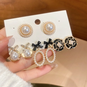 Detailed set of floral pearl earrings featuring black enamel camellia and gold bows