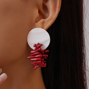 Orecchini di corallo rosso e conchiglia bianca indossati da una modella in vista laterale