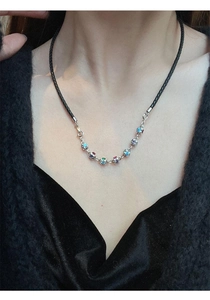 Close-up of rainbow stones necklace with silver chain and black woven cord on neck