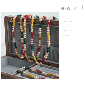 Macro detail of handmade freshwater pearl necklace with colorful beads on wooden box