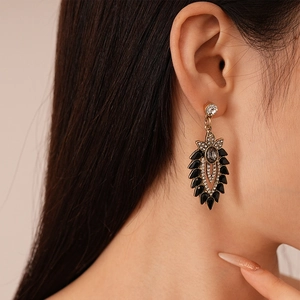 Vintage gold drop earrings with black teardrop gems and white rhinestones on model