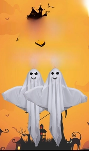 Detail of two white hanging Halloween ghosts with heart eyes on orange background