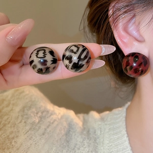 Close-up of resin round leopard print stud earrings in grey and red tones
