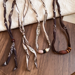 Detailed close-up of brown paisley fabric scarf necklace with ethnic wood and ceramic beads