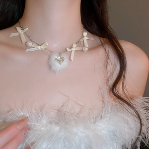 Macro shot of pearl necklace featuring a white fur ball and heart-shaped crystal