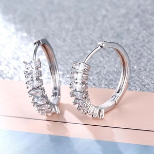 Macro detail of silver hoop earrings featuring five marquise-cut sparkling zircons