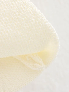 Makroaufnahme der elfenbeinfarbenen Strickweste mit Rippmuster und weichem Gewebe