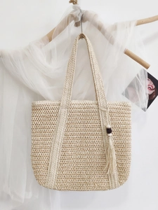 Large beige woven straw tote bag with tassel and wood bead charm for beach holidays